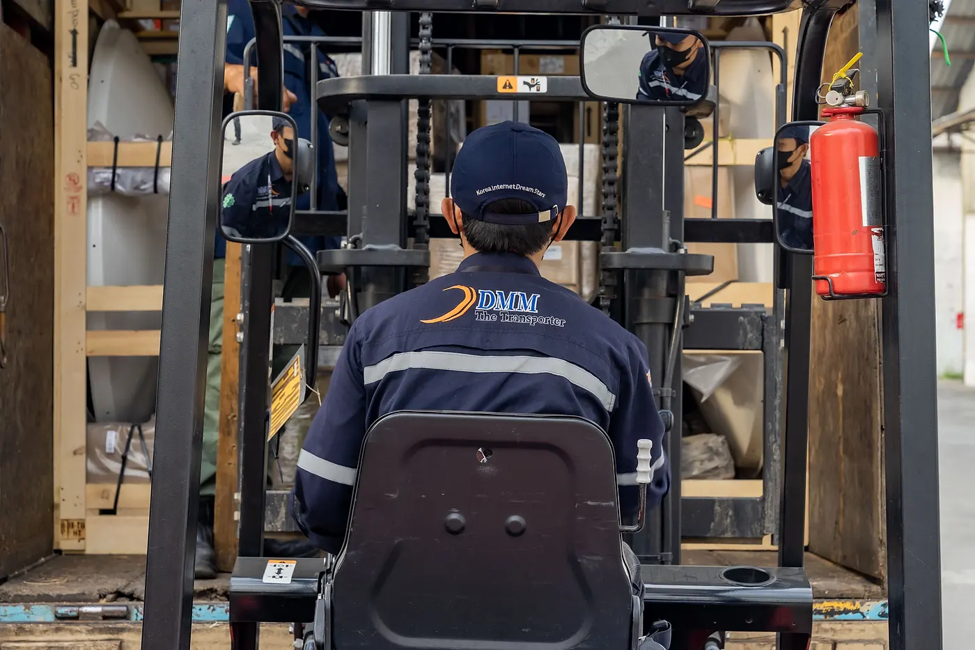 A DMM operator in uniform driving a forklift in the warehouse